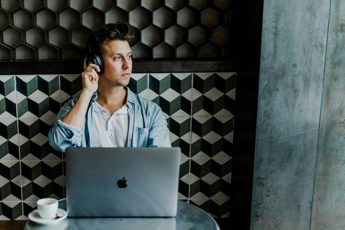 Man using headphones and sitting on front of a macbook